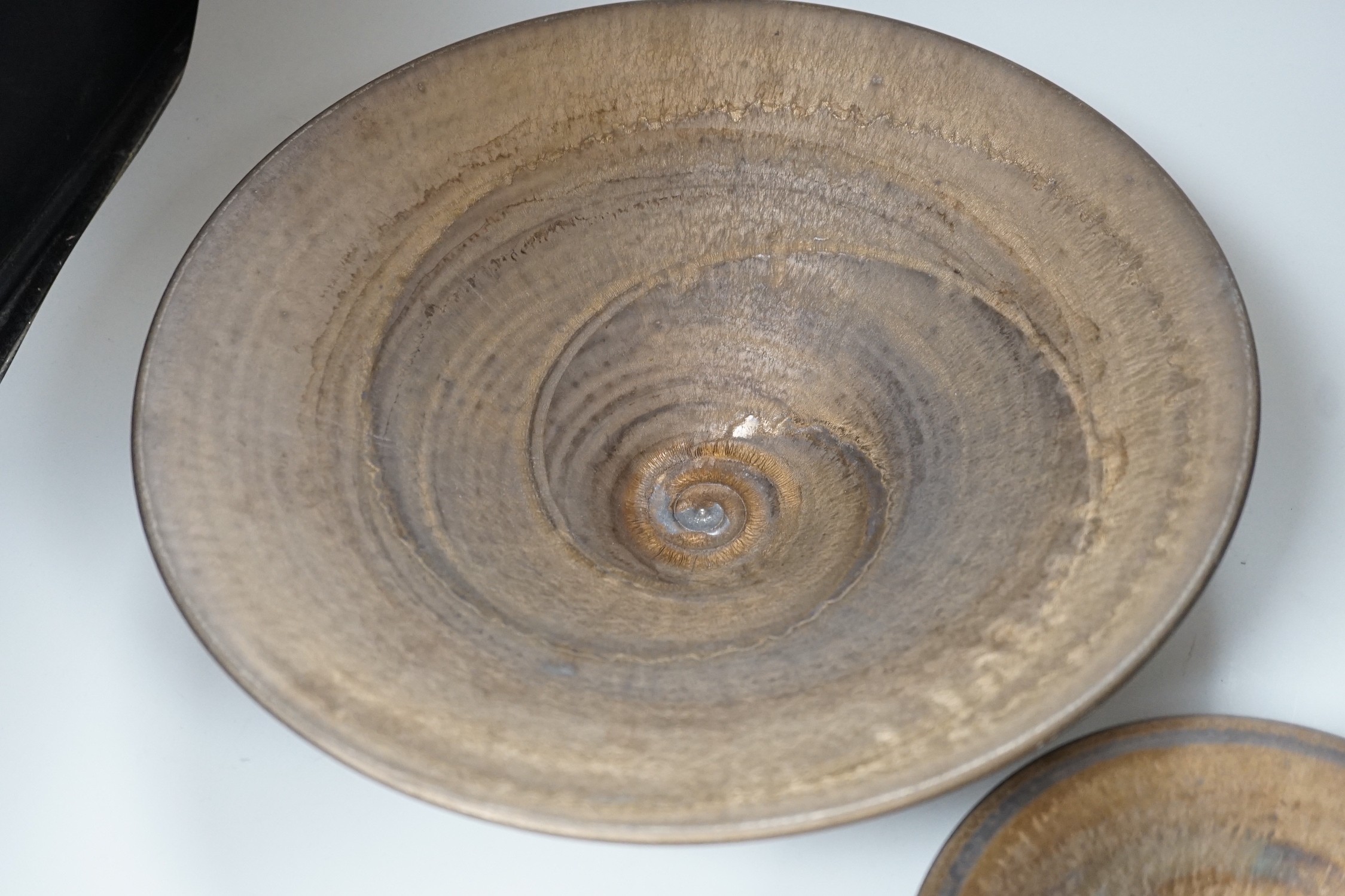 Huw Powell Roberts - two white earthenware open dishes covered in mottled bronze glaze with gold spiral decoration, incised HPR mark, 36.5cms and 19.5cms diameter